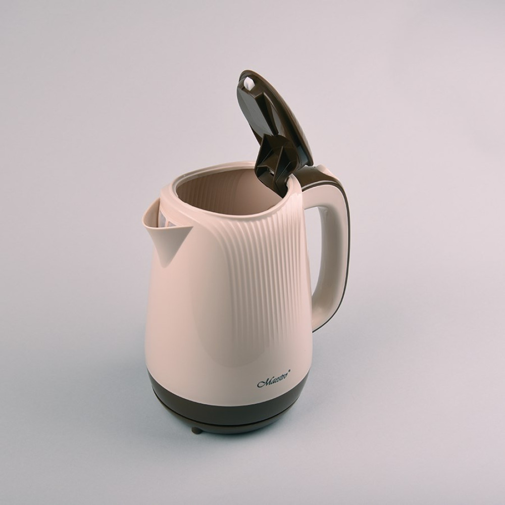 Un bollitore elettrico con coperchio aperto, color crema con accenti marroni, è su una superficie azzurra. Il marchio 'Maestro' è visibile.