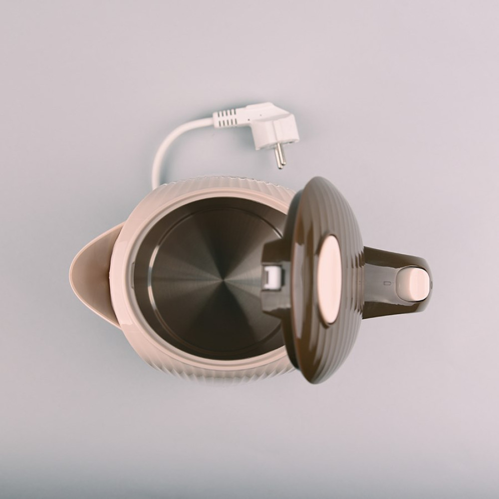 Vista dall'alto di un bollitore elettrico beige aperto con coperchio marrone e cavo di alimentazione e spina bianca su una superficie grigio chiaro.