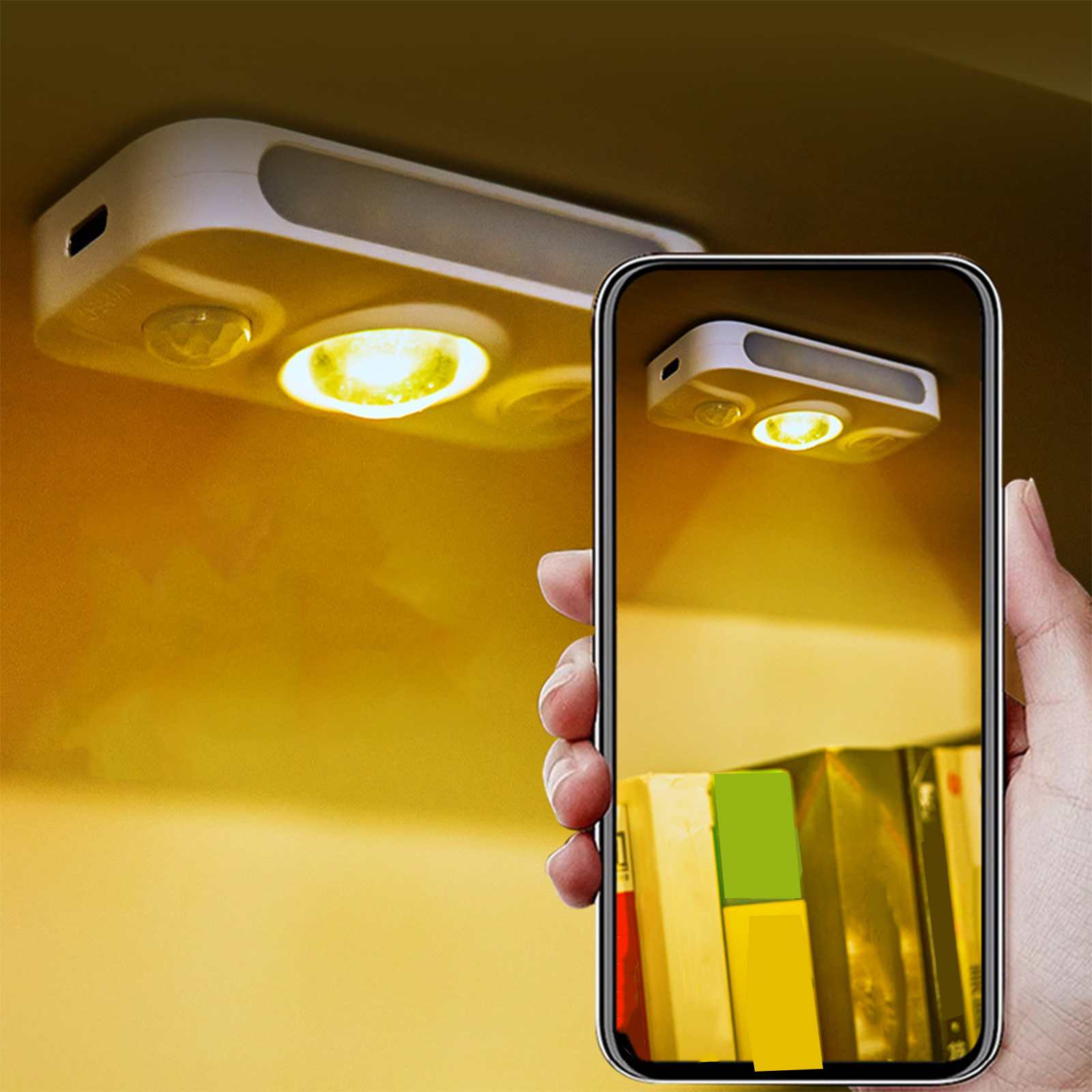 Eine Hand hält ein Telefon, das eine Leuchte zeigt. Die eigentliche Leuchte ist oben montiert, beide sind beleuchtet. Bücher sind darunter sichtbar.
