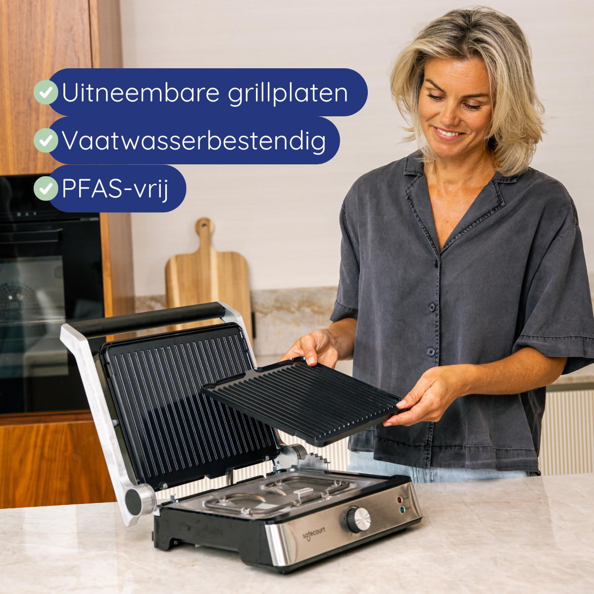 Woman holding a black grill plate, a grill is open on a marble counter. Text indicates removable plates, dishwasher safe, and PFAS-free.