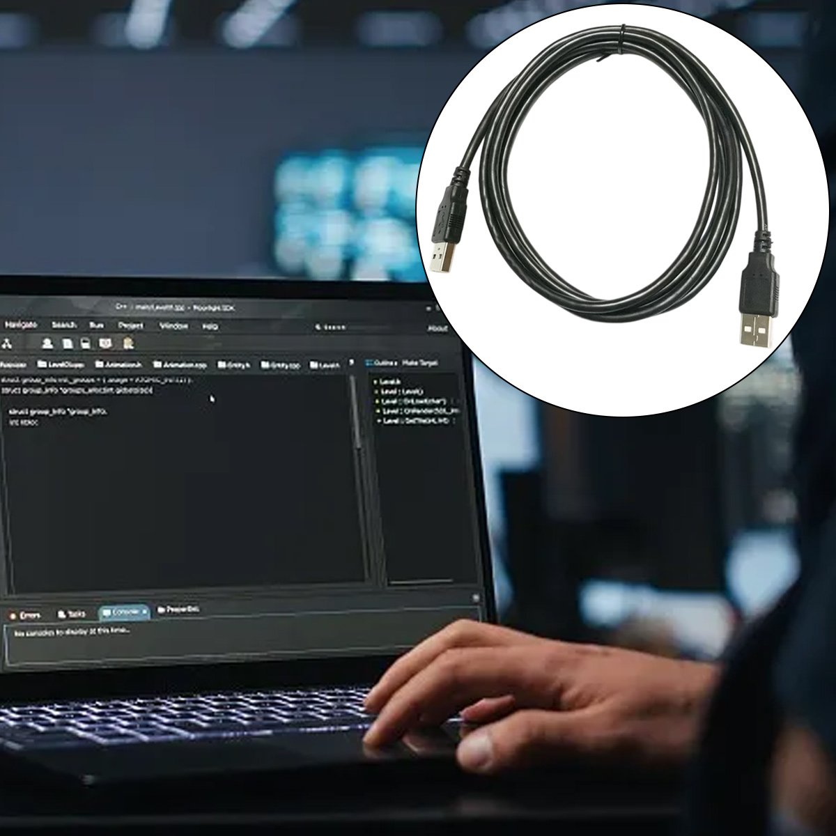 Ein schwarzes USB-Kabel ist über einem Laptop aufgerollt, der Code anzeigt. Eine Hand liegt auf der Laptop-Tastatur. Der Hintergrund ist verschwommen.