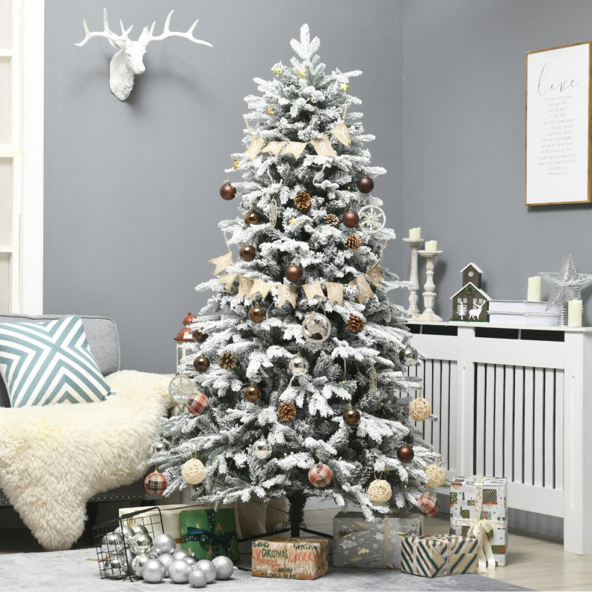 Ein geschmückter Weihnachtsbaum mit Ornamenten, Geschenken darunter und einem Hirschkopf an einer grauen Wand. Eine gemütliche Szene mit Couch.