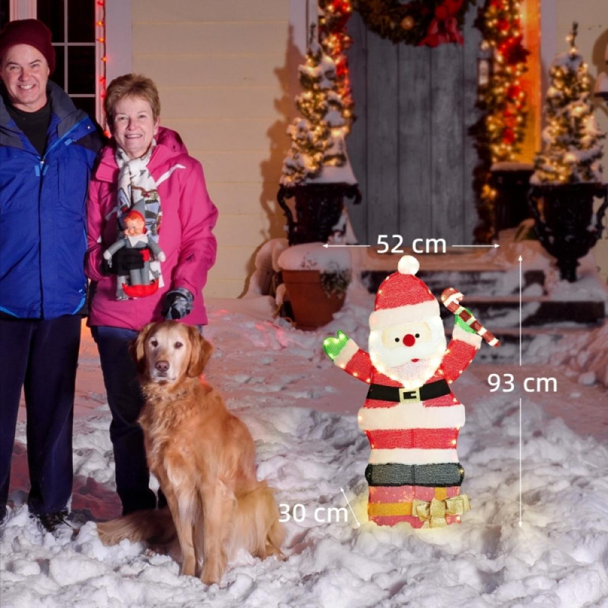 Drei Personen, ein Hund und ein leuchtender Weihnachtsmann stehen im Schnee. Im Hintergrund eine dekorierte Tür. Der Weihnachtsmann ist 93 cm groß.