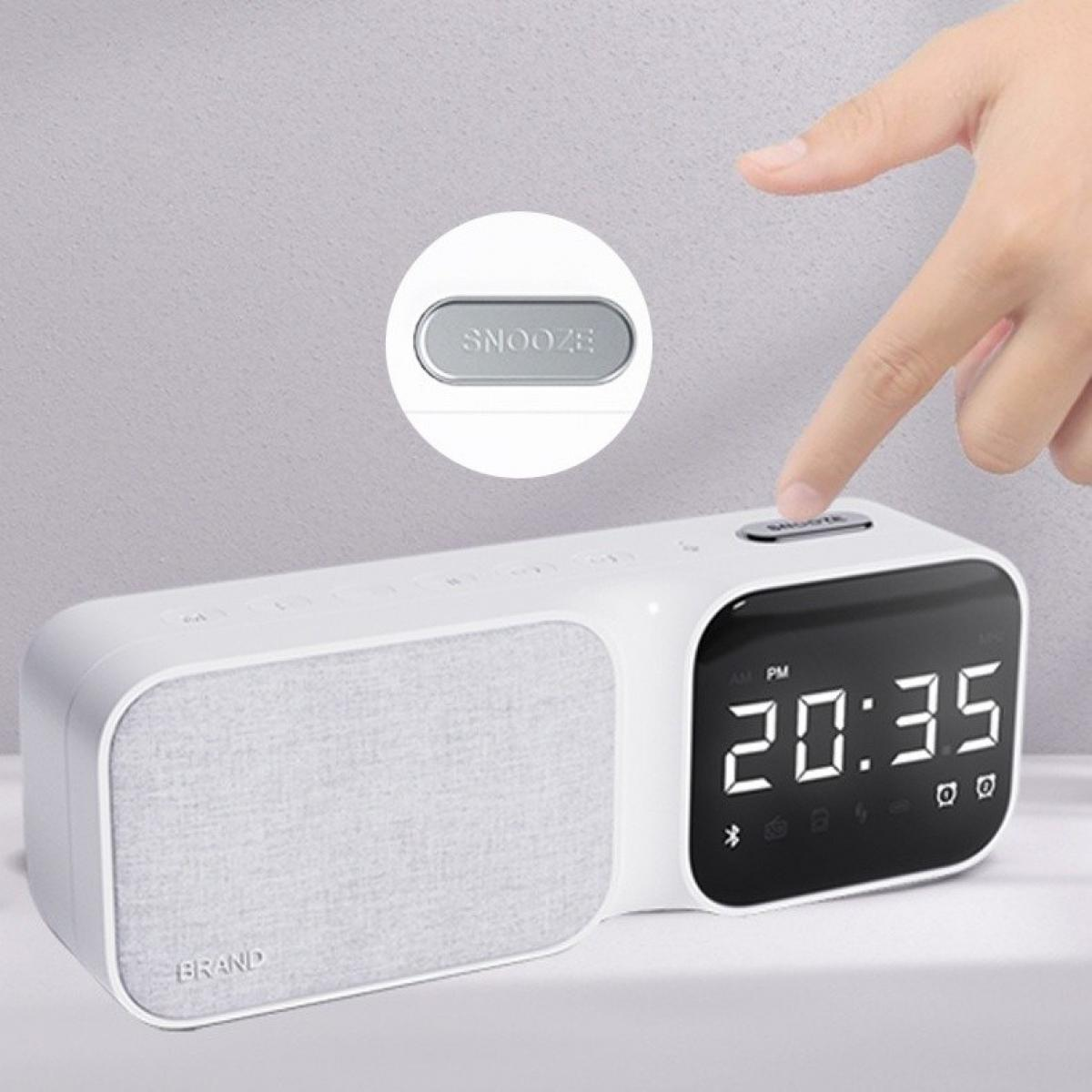 Ein weißer Wecker zeigt 20:35 an. Eine Hand drückt die Schlummertaste. Die Uhr hat einen Lautsprecher mit dem Markennamen.