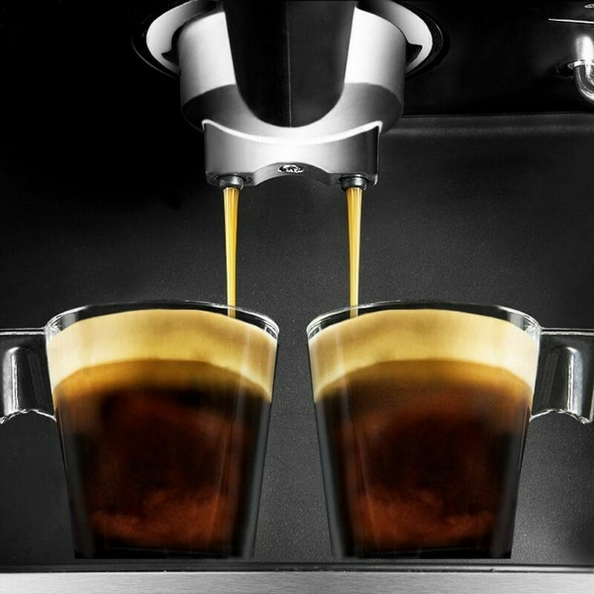 Macchina da caffè che eroga espresso in due tazze di vetro trasparente. Il caffè è marrone scuro con una crema.
