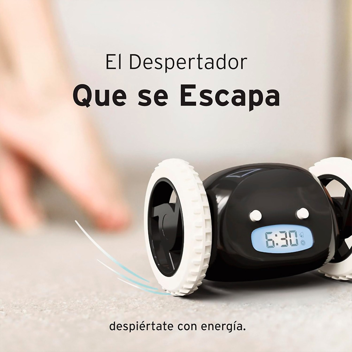 Reloj negro con ruedas blancas, mostrando 6:30. Texto en español. Una mano a punto de tocar el reloj, que está sobre una superficie gris.