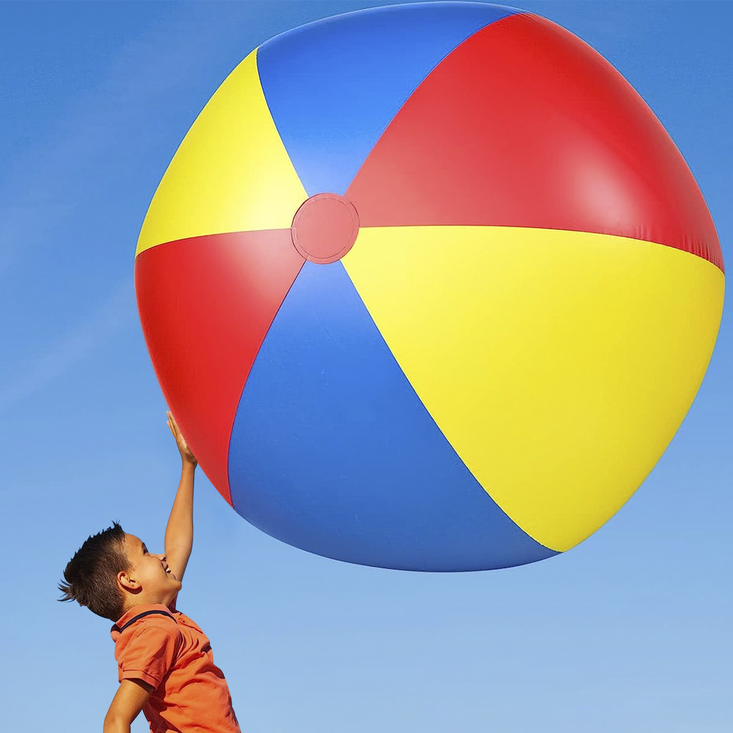 Un niño alcanza una gran pelota de playa colorida contra un cielo azul claro. La pelota es roja, amarilla y azul.