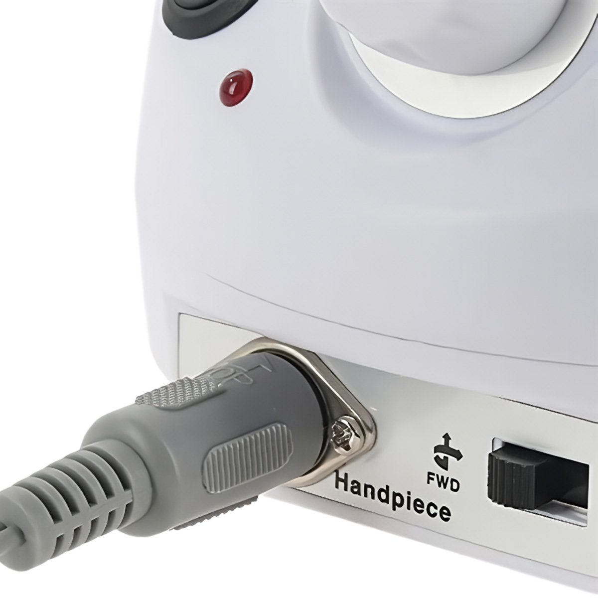 Primer plano de un dispositivo blanco con un cable de alimentación gris enchufado. Hay una luz roja y un interruptor con la etiqueta 'Handpiece'.