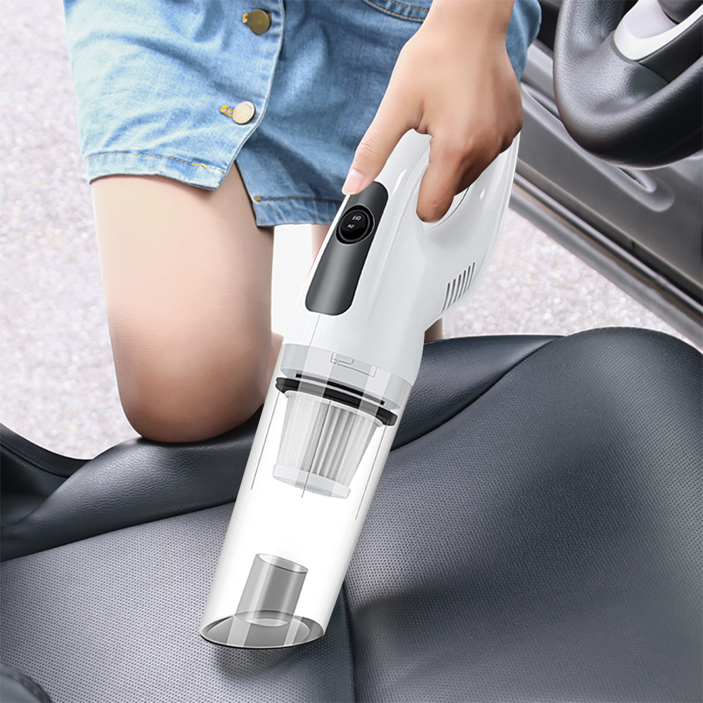 Eine Person hält einen weißen Staubsauger über einem Autositz. Der Staubsauger ist an. Ein Jeansrock ist sichtbar.