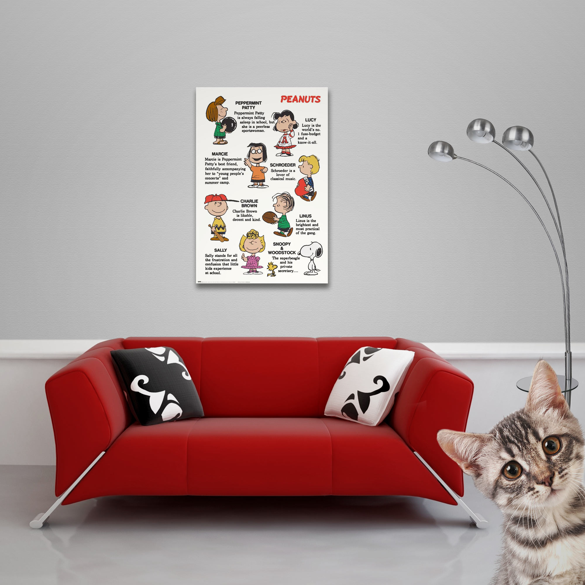 Rotes Sofa mit Kissen und Peanuts-Poster. Eine Katze im Vordergrund. Eine Lampe rechts.