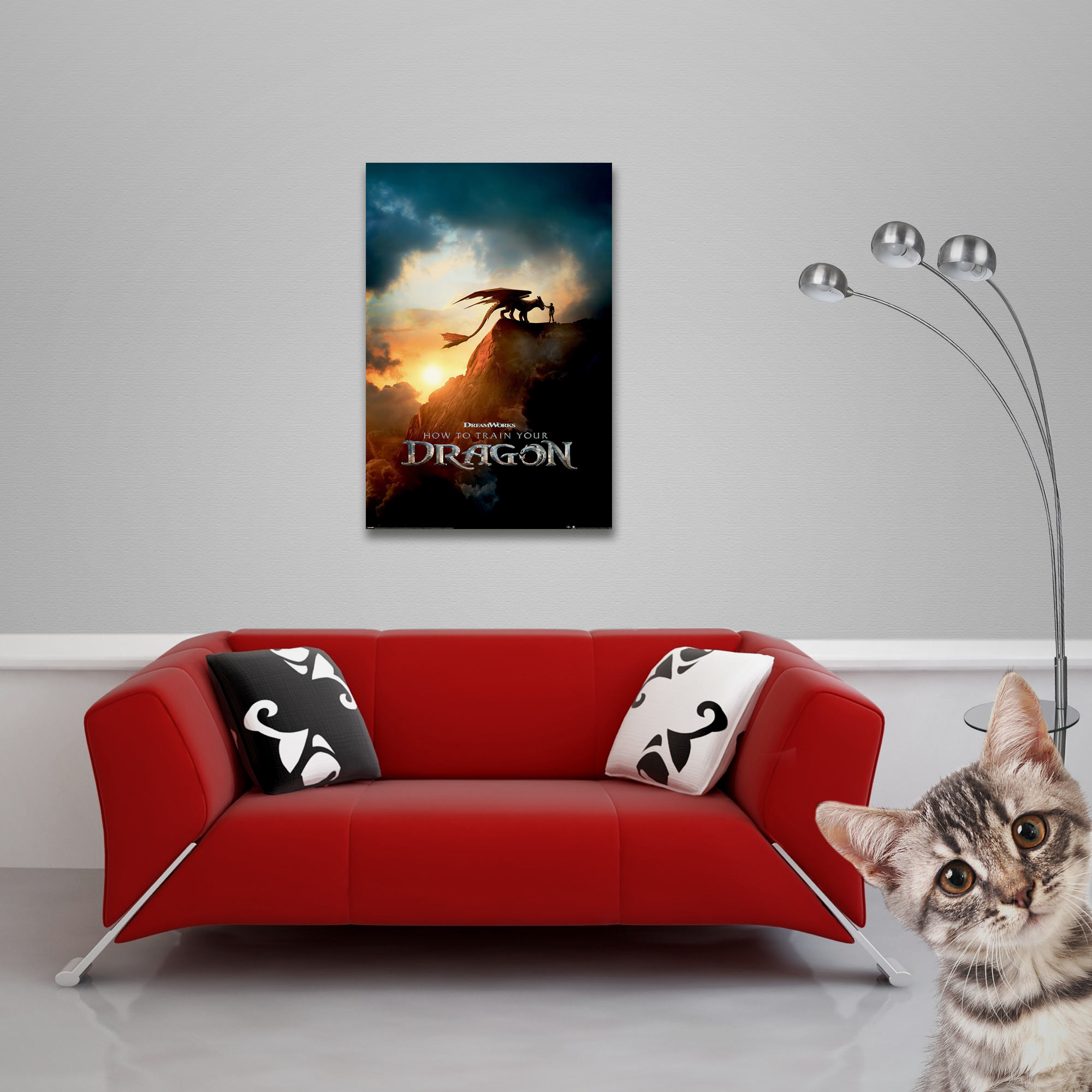 Ein rotes Sofa mit schwarz-weißen Kissen, ein Poster, eine Lampe und eine Katze, die in die Kamera schaut.