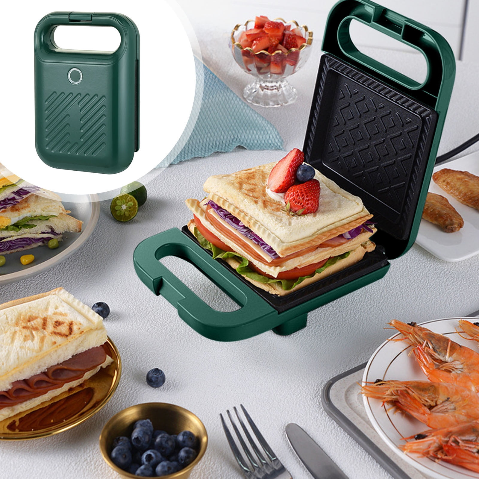 Grüner Sandwichmaker mit Sandwich. Erdbeeren, Blaubeeren und Garnelen sind auch auf dem weißen Tisch zu sehen.