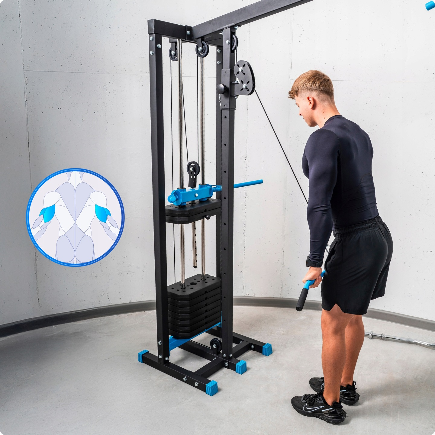 Mężczyzna używa wyciągu. Maszyna jest czarna i niebieska. Mężczyzna ma na sobie czarne spodenki i koszulkę z długim rękawem.