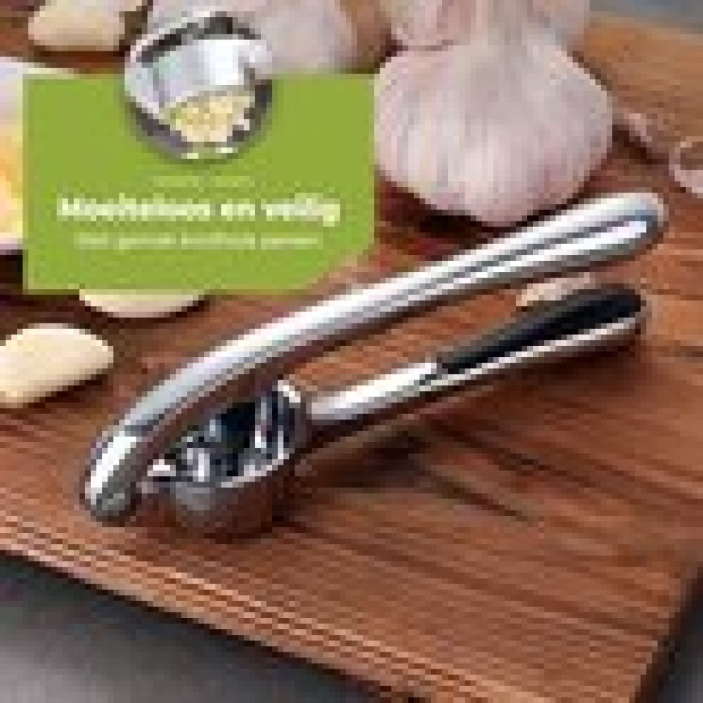 Eine Knoblauchpresse aus Metall auf einem Holzbrett. Knoblauchknollen und -zehen sind sichtbar. Ein grünes Schild mit Text befindet sich im Hintergrund.