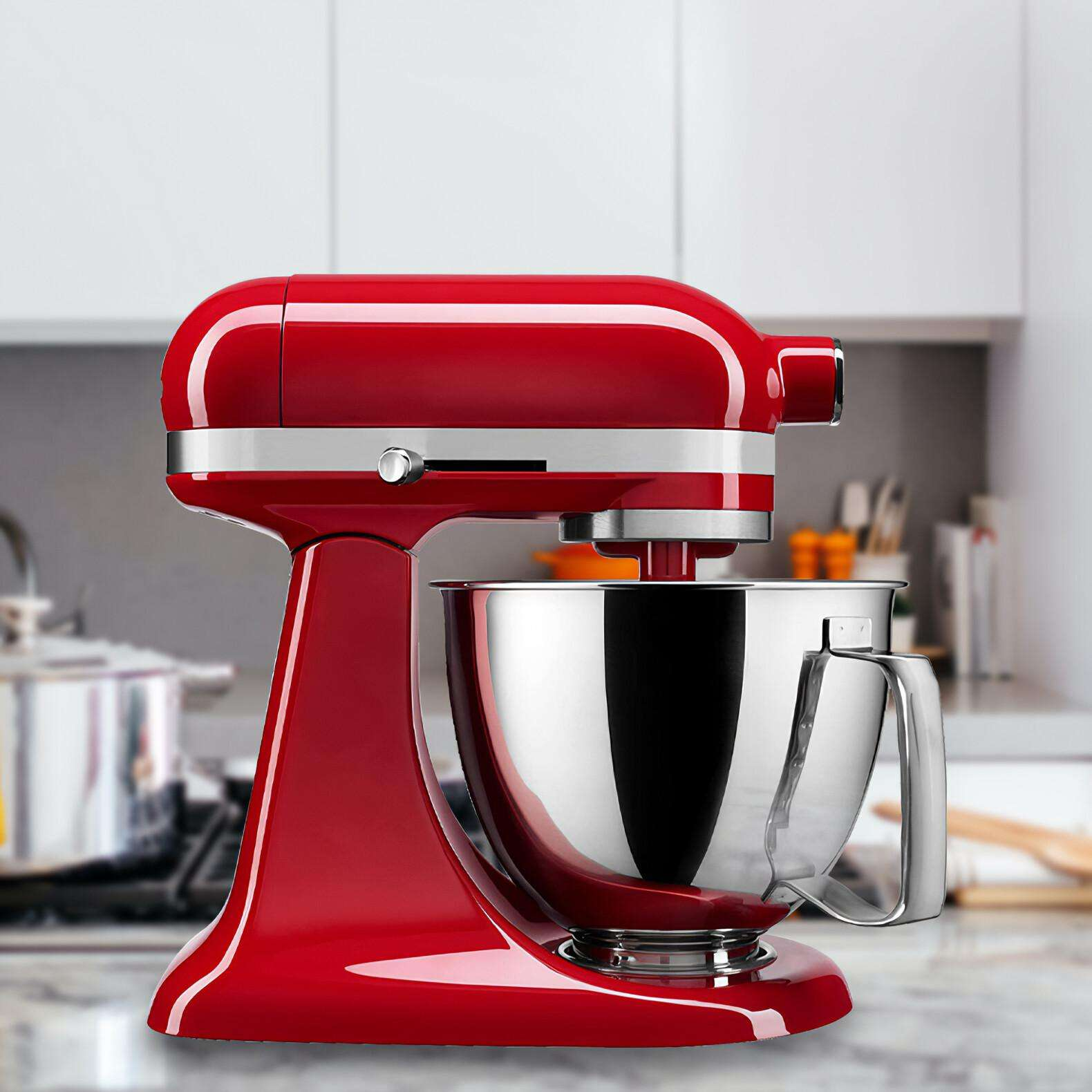 Ein roter KitchenAid-Küchenmixer mit einer Edelstahlschüssel. Er steht auf einer Marmorarbeitsplatte in einer Küche.