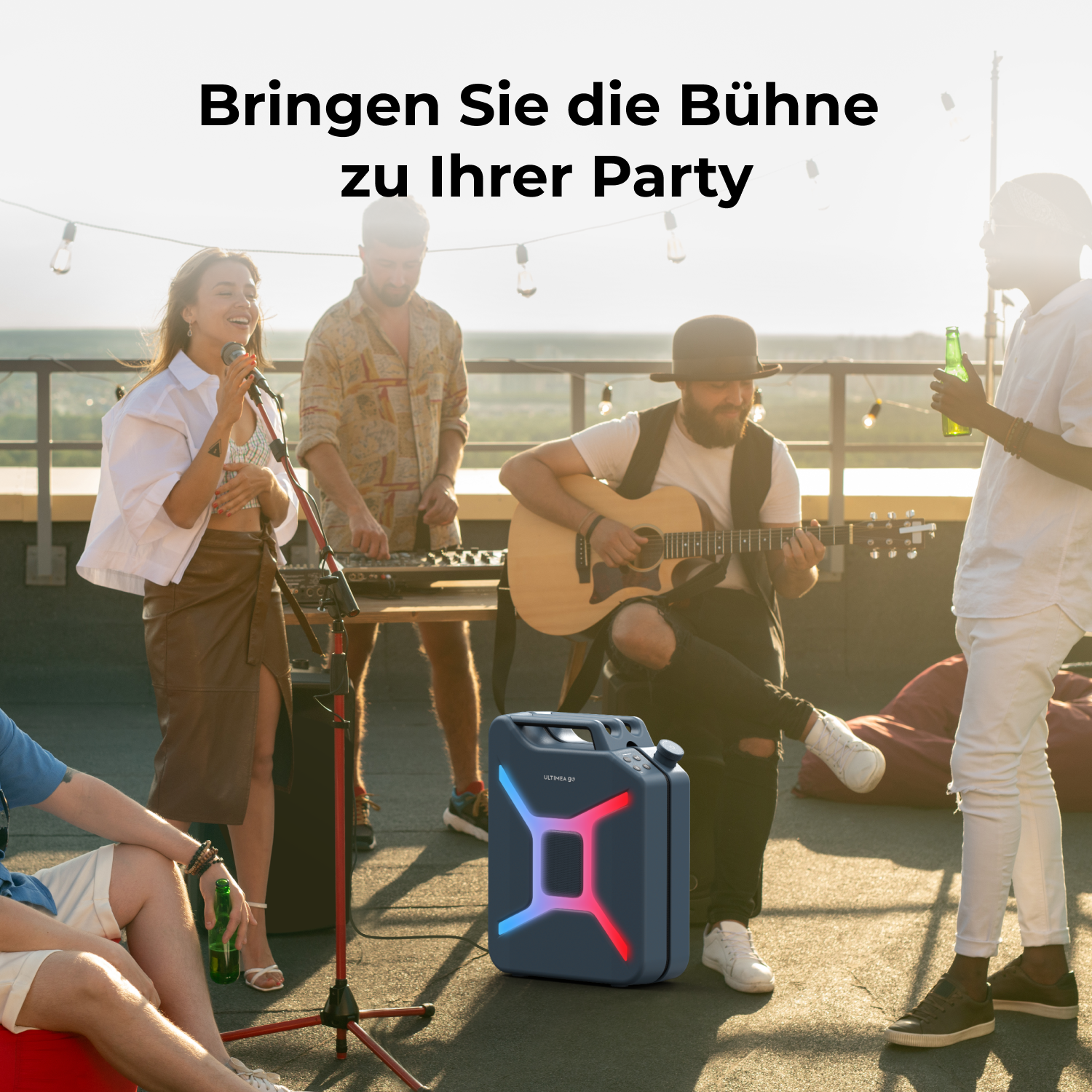 Band spielt auf einem Dach, mit einem Lautsprecher im Vordergrund. Leute singen, spielen Gitarre und halten Getränke. Sonnenuntergang im Hintergrund.