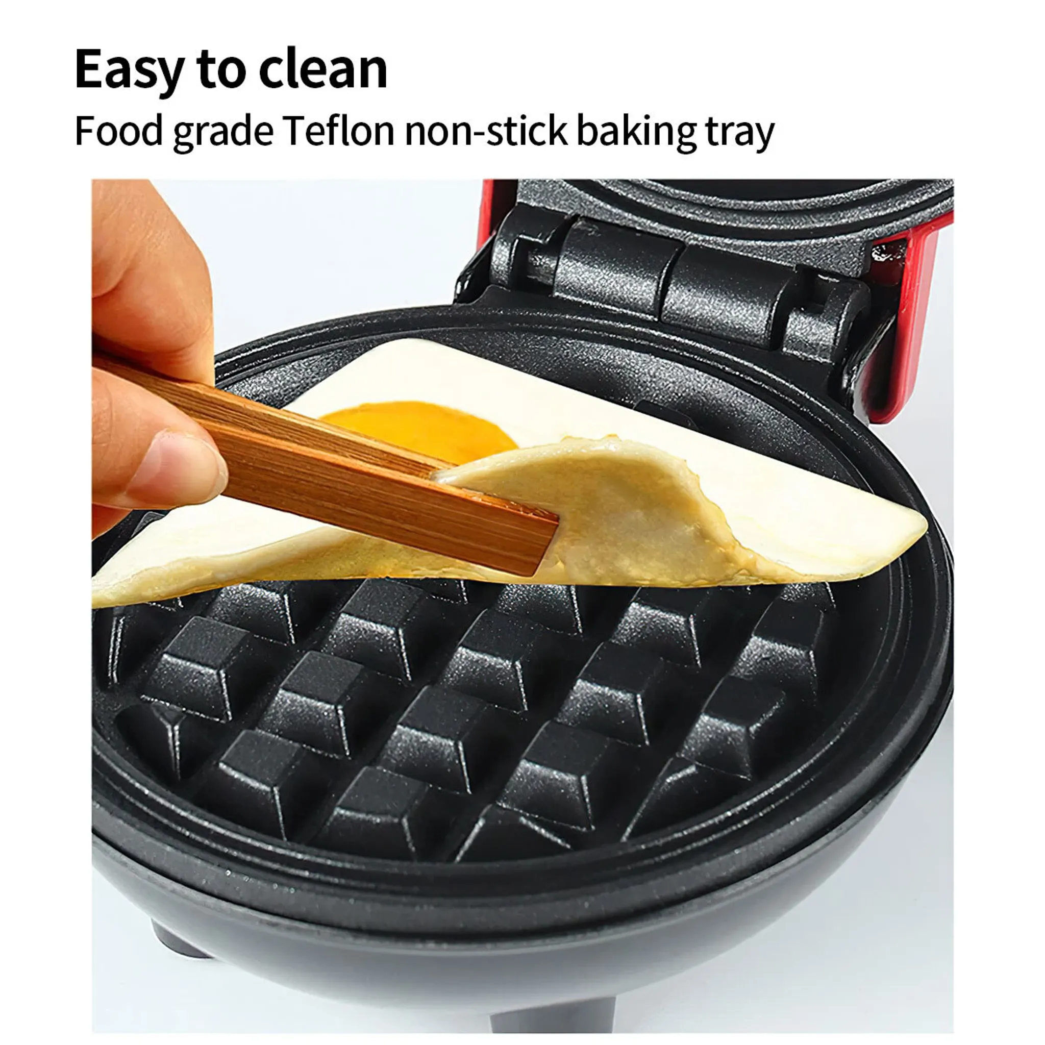 Eine Hand benutzt eine Holzzange, um einen gekochten Waffel aus einem Waffeleisen zu nehmen. Das Gerät ist schwarz.