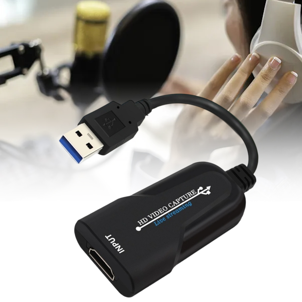 Schwarzes HD-Videoaufnahmegerät mit USB- und HDMI-Anschlüssen. Im Hintergrund eine Person mit Kopfhörern.