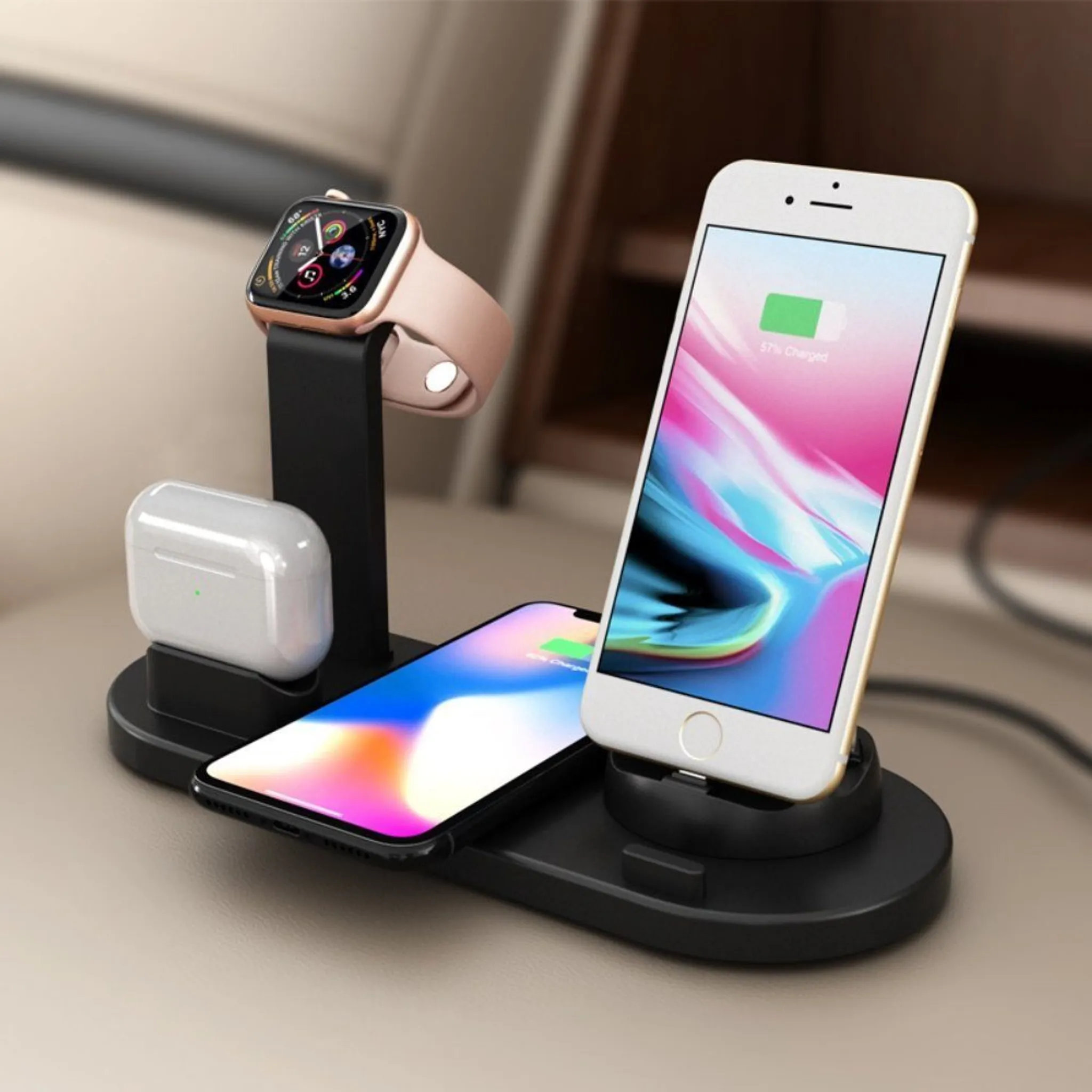 Ladestation mit Telefon, Uhr und Ohrhörern. Telefon zeigt 57 % geladen an. Die Uhr hat ein rosa Armband. Weiße Ohrhörer sind ebenfalls vorhanden.