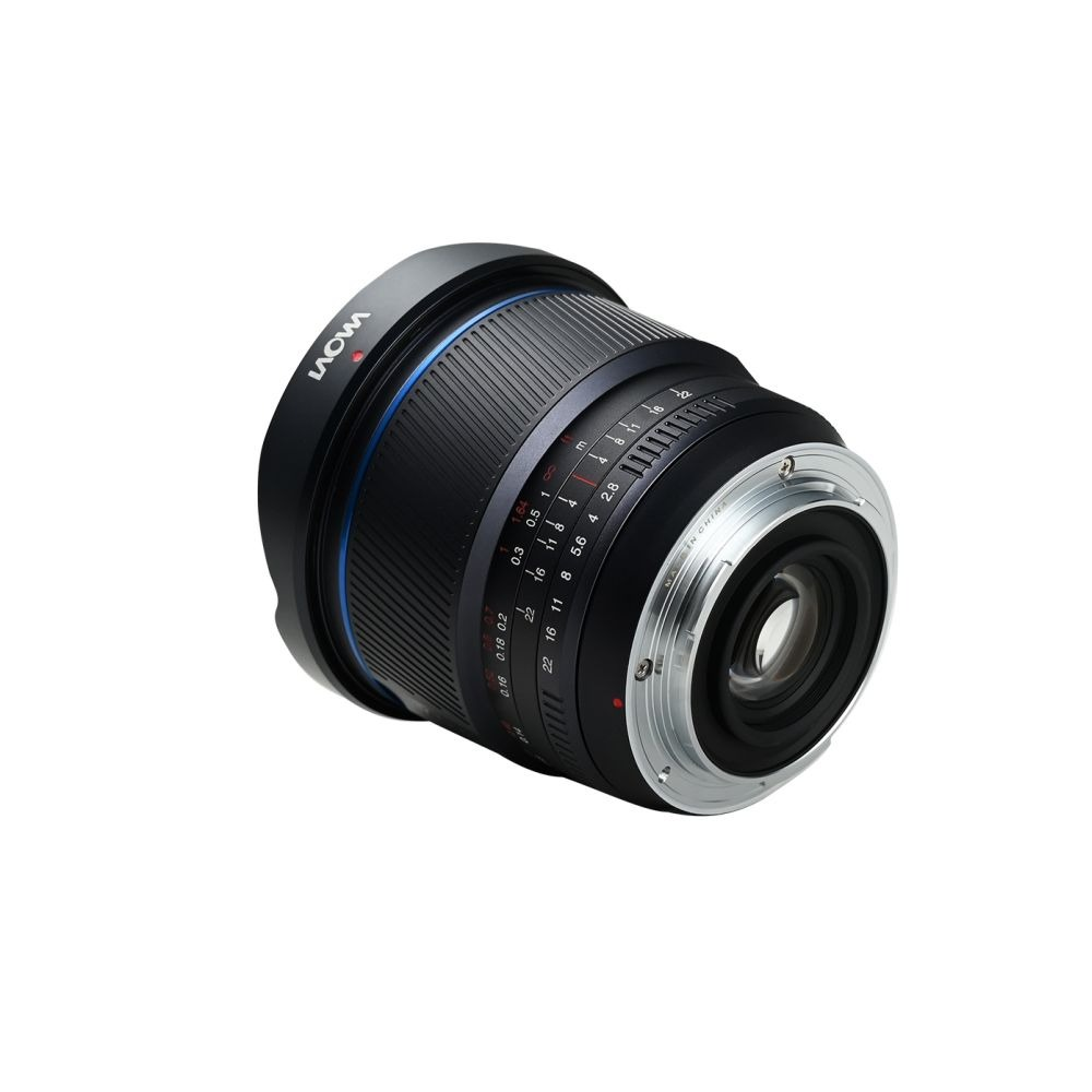 Un objetivo de cámara negro con detalles azules y anillo plateado. Inclinado sobre fondo blanco. Marcas indican distancias focales y apertura.