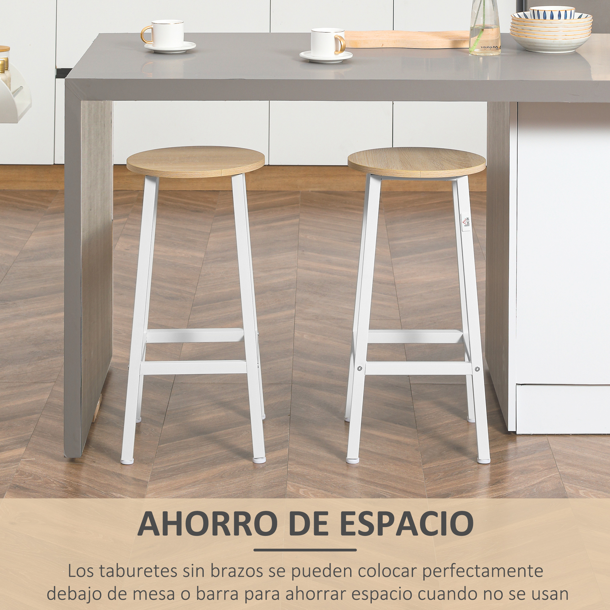 Dos taburetes con patas blancas y asientos de madera están frente a una encimera gris. Hay tazas y platos en la encimera.