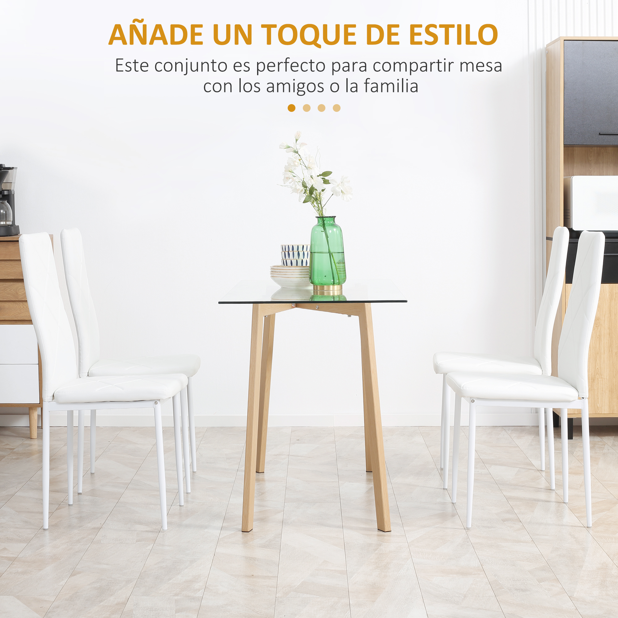 Una mesa de comedor con sillas blancas. Un jarrón verde con flores sobre la mesa. El fondo es una pared blanca.
