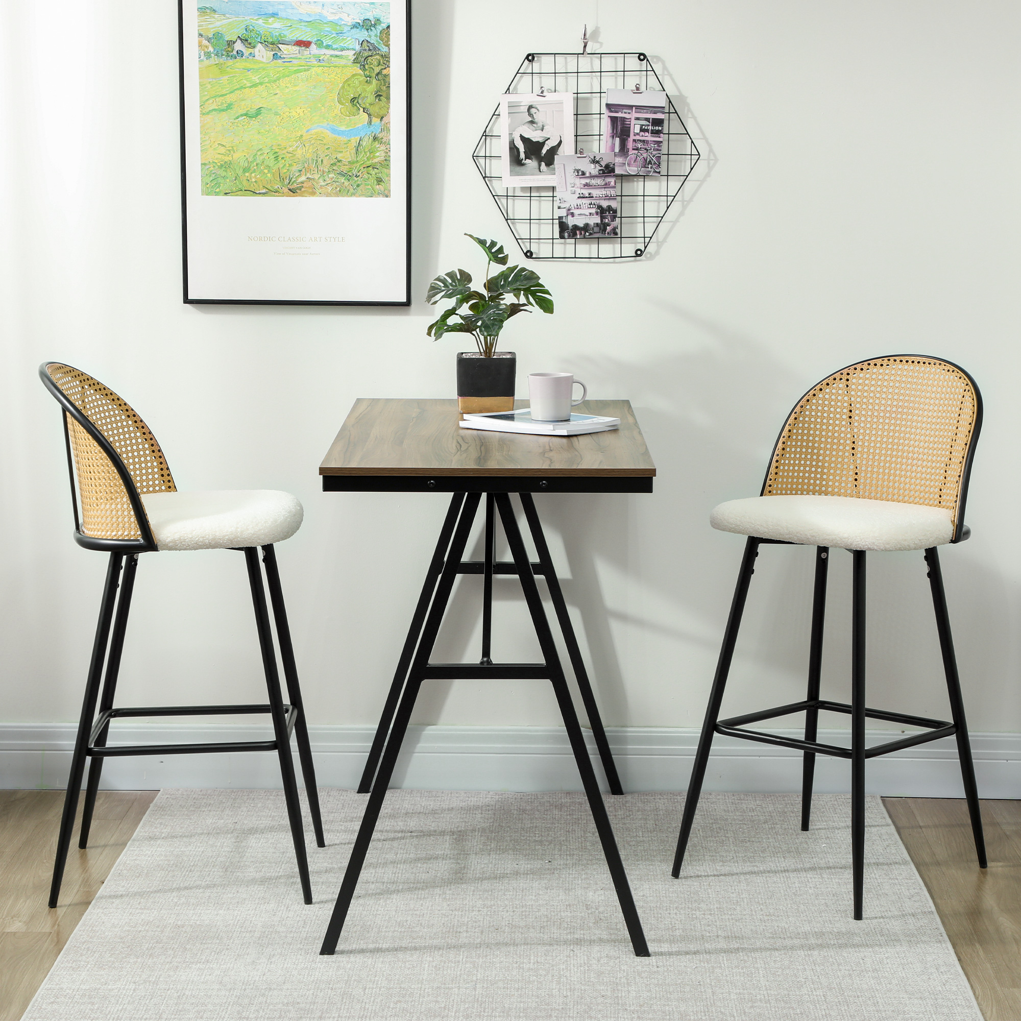 Una habitación con una mesa pequeña, dos taburetes y una obra de arte enmarcada colgada en la pared. Hay una planta en la mesa.