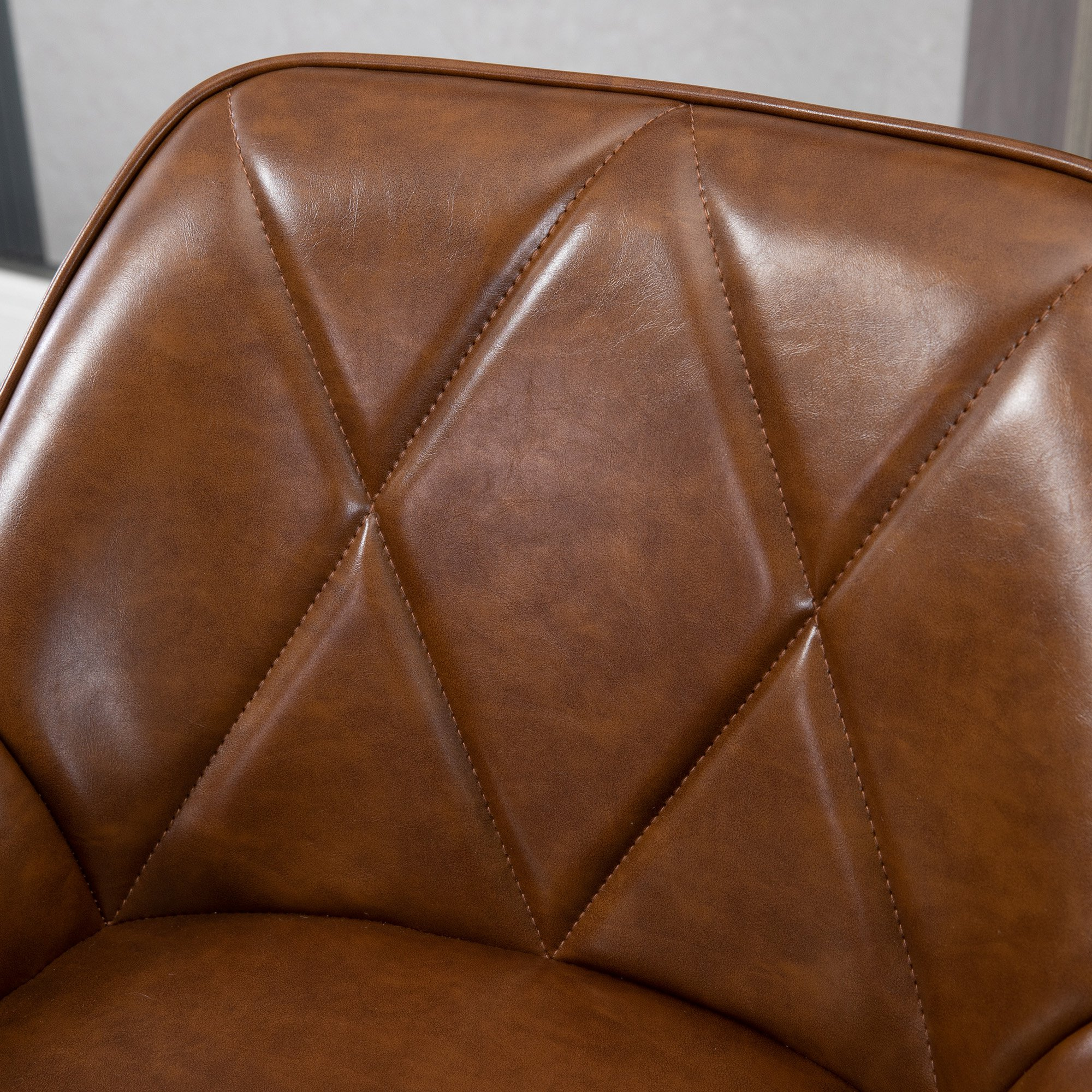 Primer plano del respaldo de una silla de cuero marrón. El cuero está acolchado con patrones de diamantes y cosido.