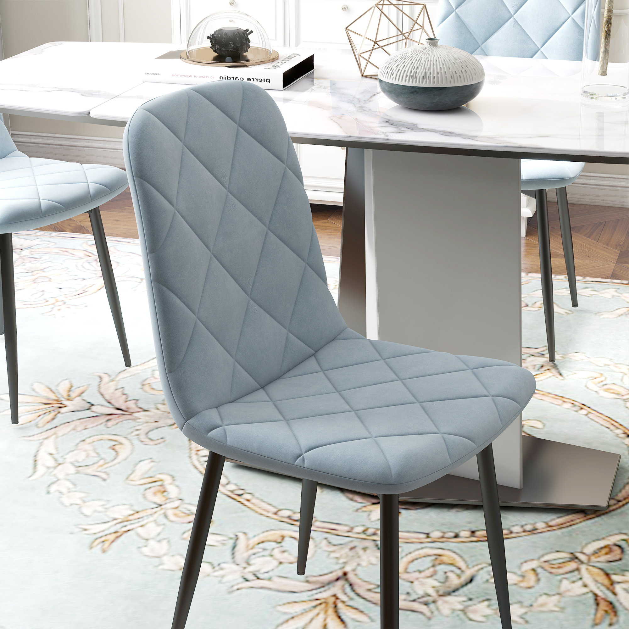 Una silla acolchada azul claro frente a una mesa de mármol blanco. La silla tiene patas negras y la escena está en una habitación luminosa.