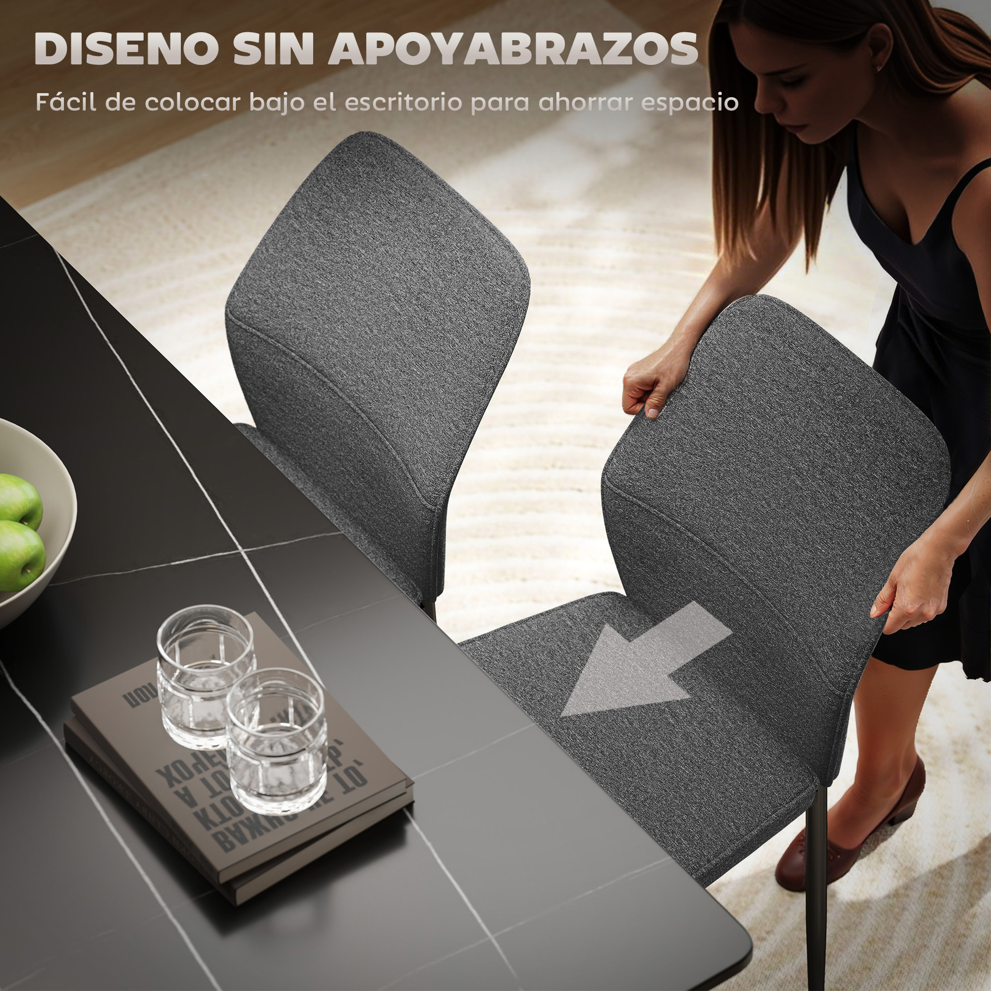 Una mujer coloca una silla gris cerca de una mesa con vasos y un libro. La mesa es negra con líneas blancas. Manzanas verdes en un cuenco.