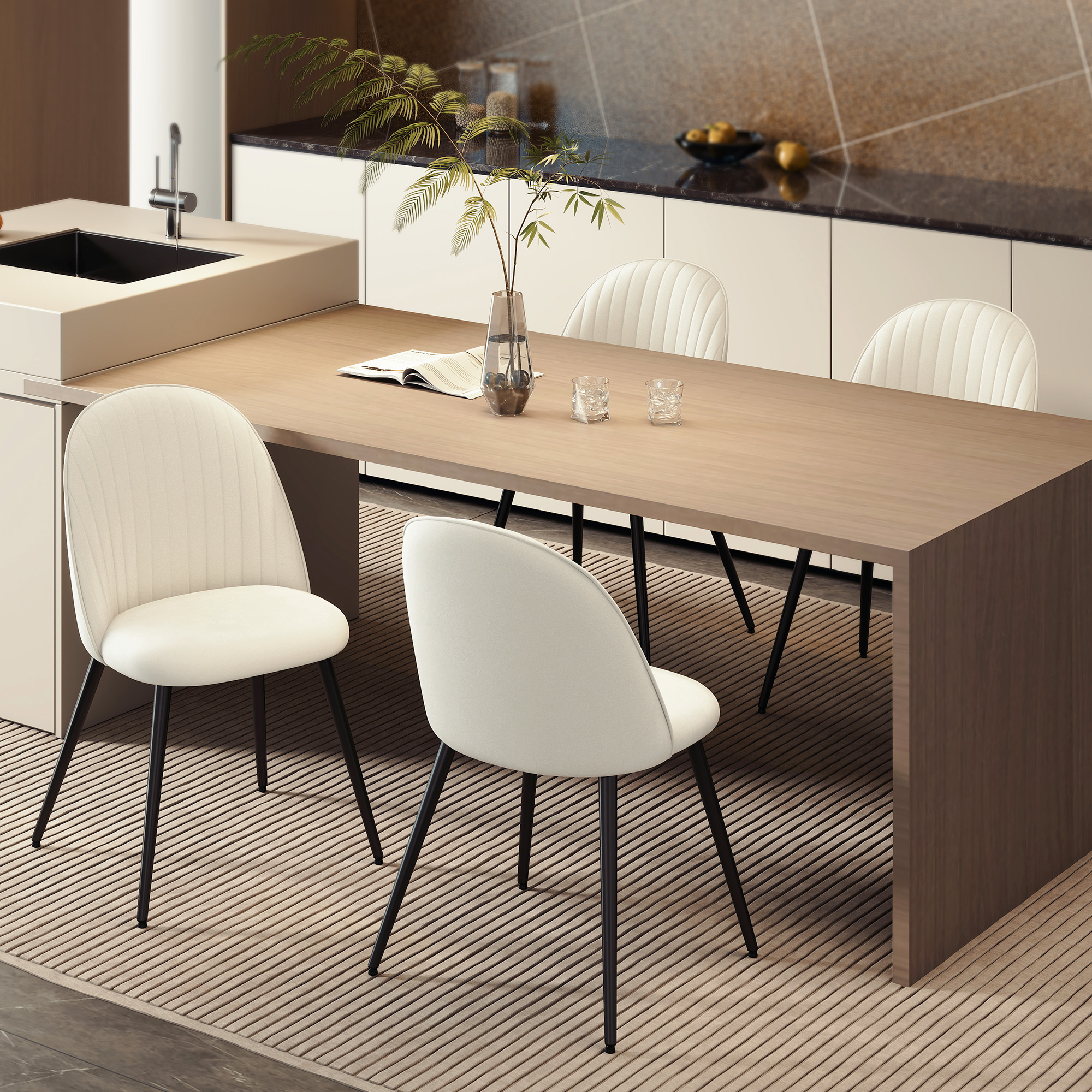 Una mesa de comedor con cuatro sillas blancas. Un jarrón con hojas verdes está sobre la mesa. Cocina al fondo.
