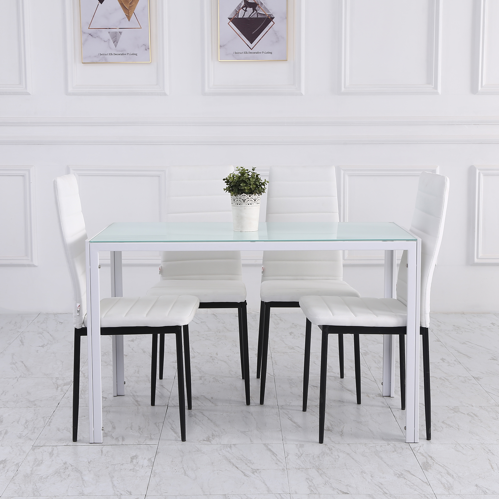 Una mesa de comedor con tapa de cristal y sillas blancas. Una pequeña planta en el centro.