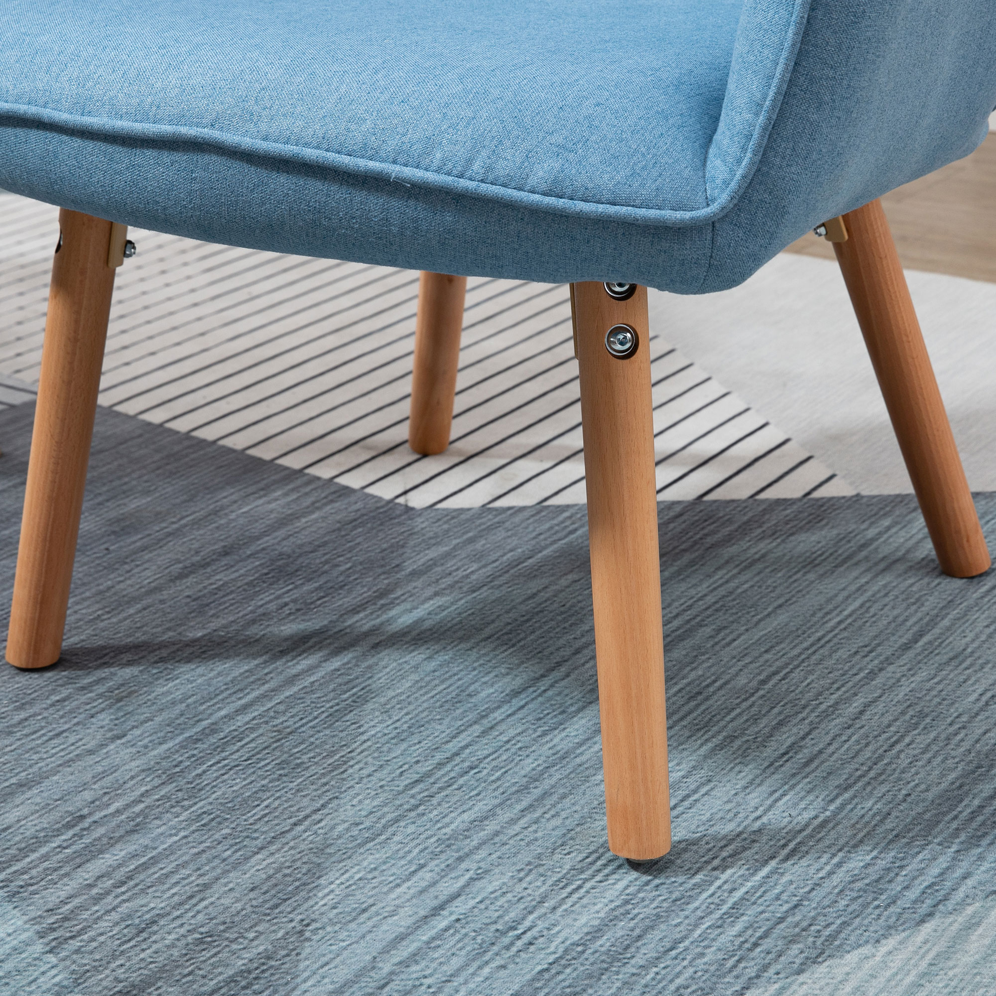 Silla azul con patas de madera sobre alfombra estampada. Enfoque en patas y asiento.