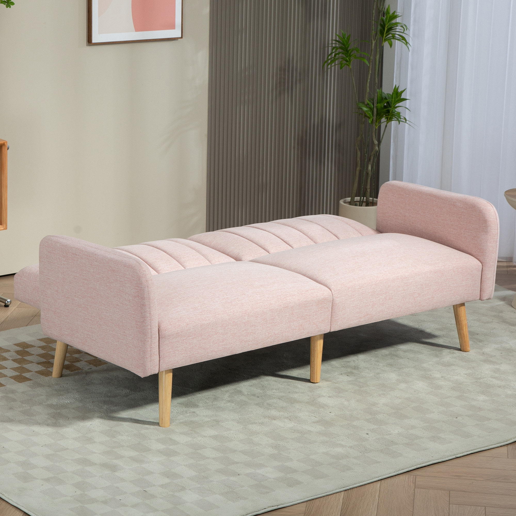 Un sofá rosa con patas de madera sobre una alfombra estampada. Fondo: pared, pintura y planta.