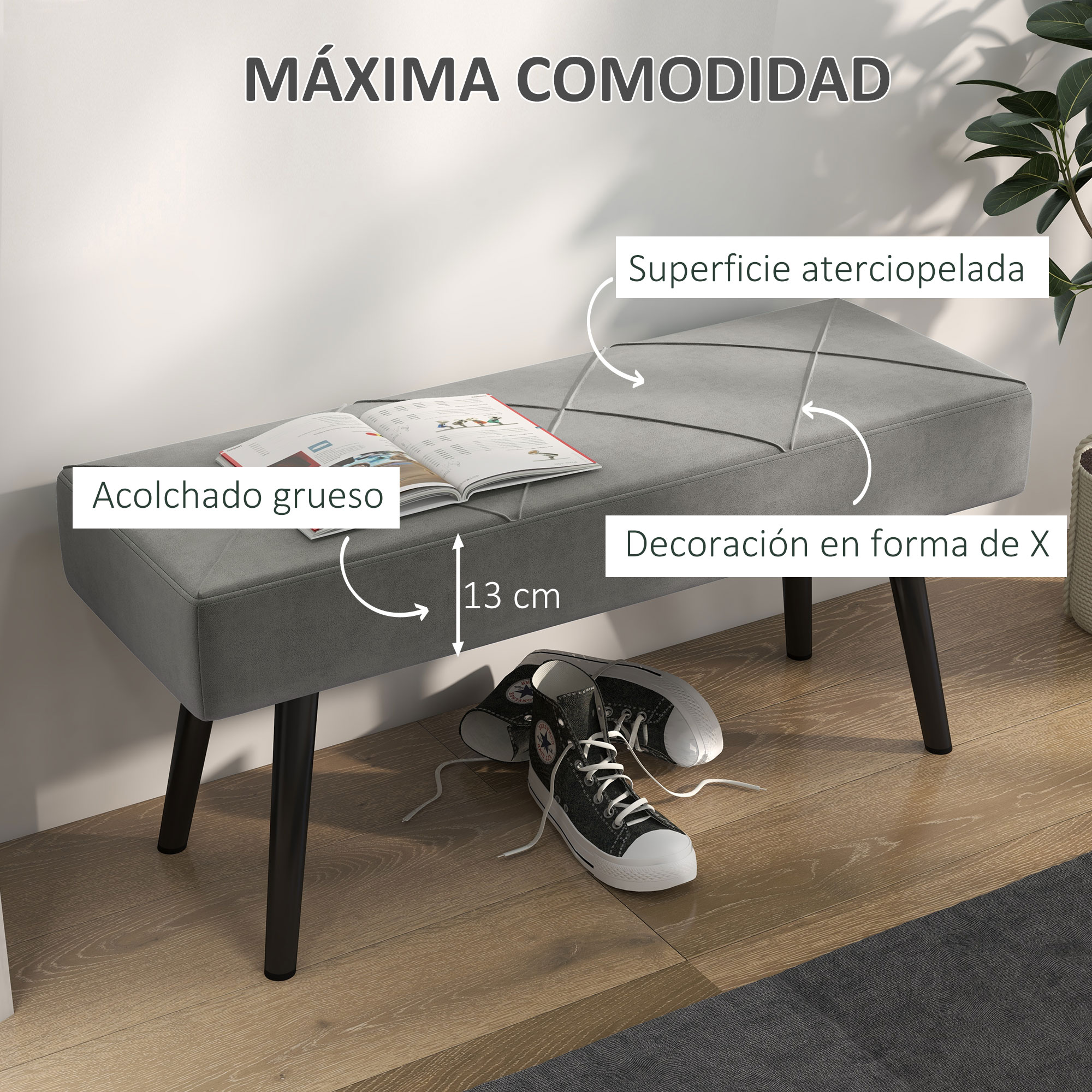 Un banco gris tapizado con patas negras. Zapatillas y un libro abierto sobre él. Patrón decorativo en X en la parte superior.