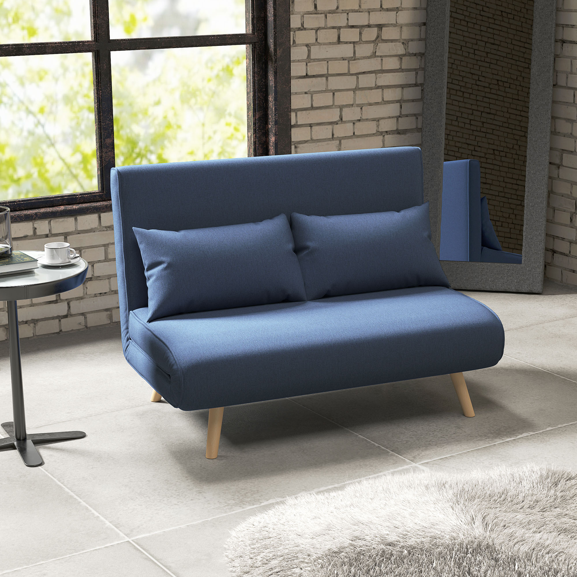Sofá azul con dos almohadas, ventana, pared de ladrillo, espejo, mesita con taza y alfombra.