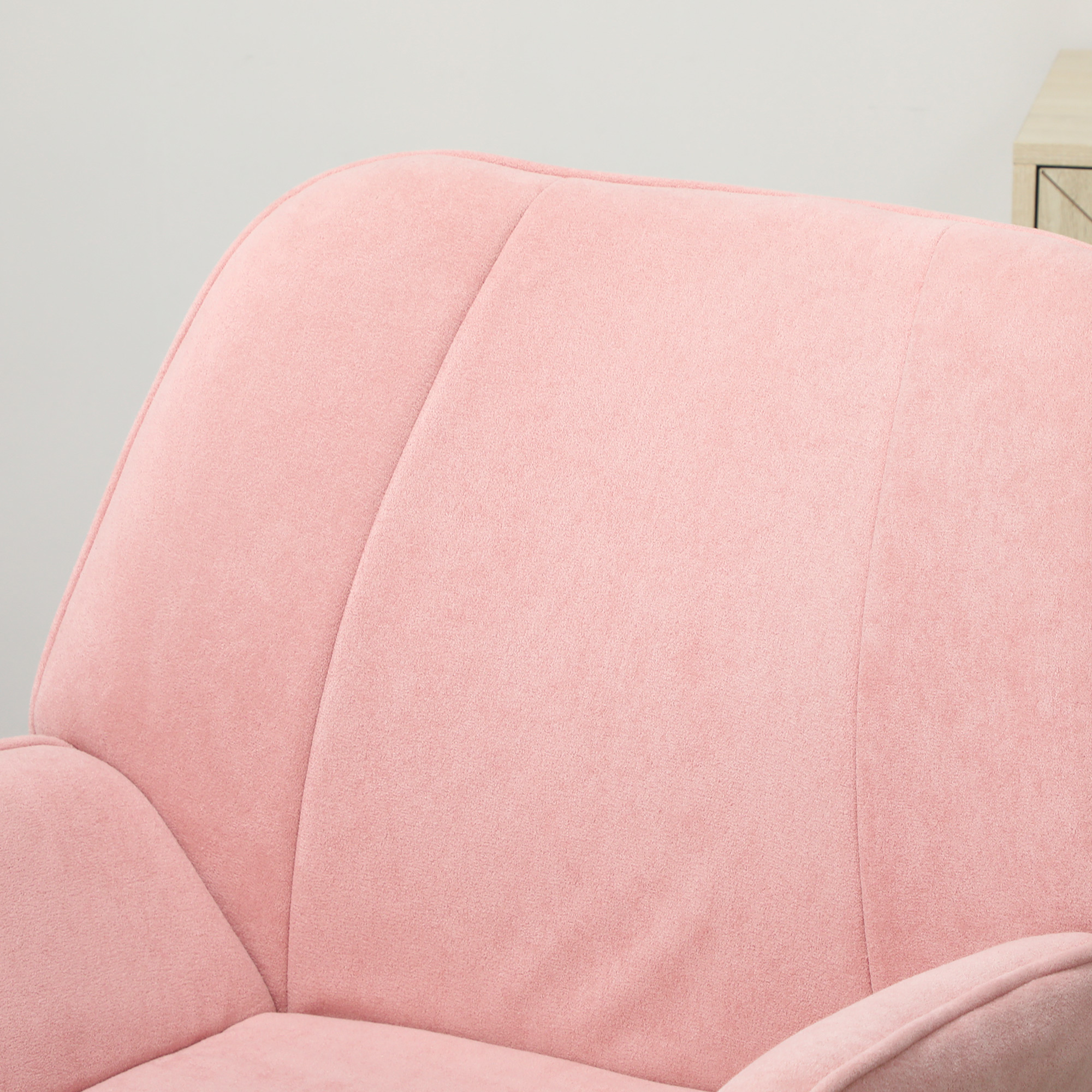 Primer plano de un sillón rosa tapizado con costuras visibles. Una pared clara forma el fondo con la esquina de un armario.
