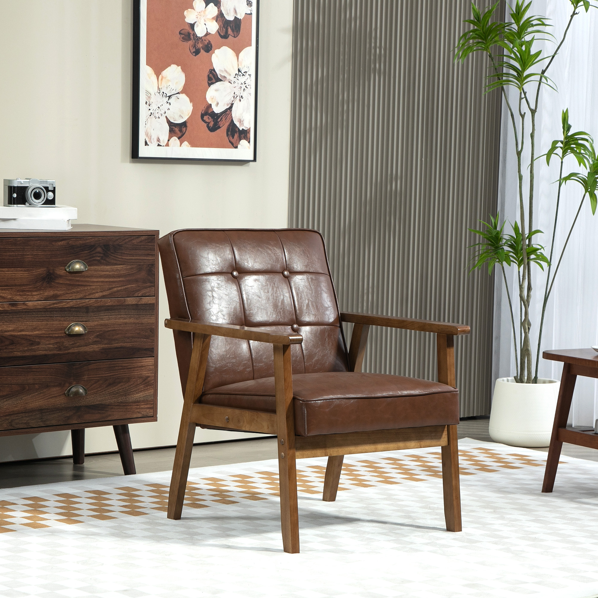 Un sillón de cuero marrón con estructura de madera se encuentra en una habitación con una pintura, una cómoda y una planta.