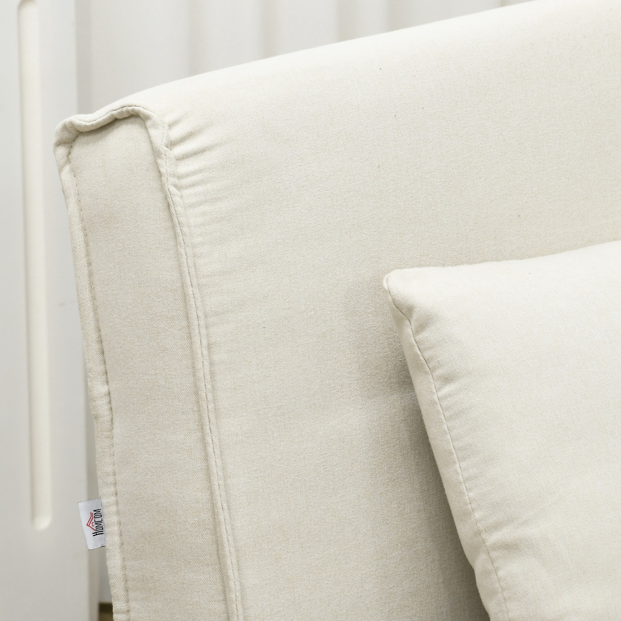 Primer plano del respaldo y la almohada de un sofá color crema. Una etiqueta pequeña con un logotipo está adjunta.