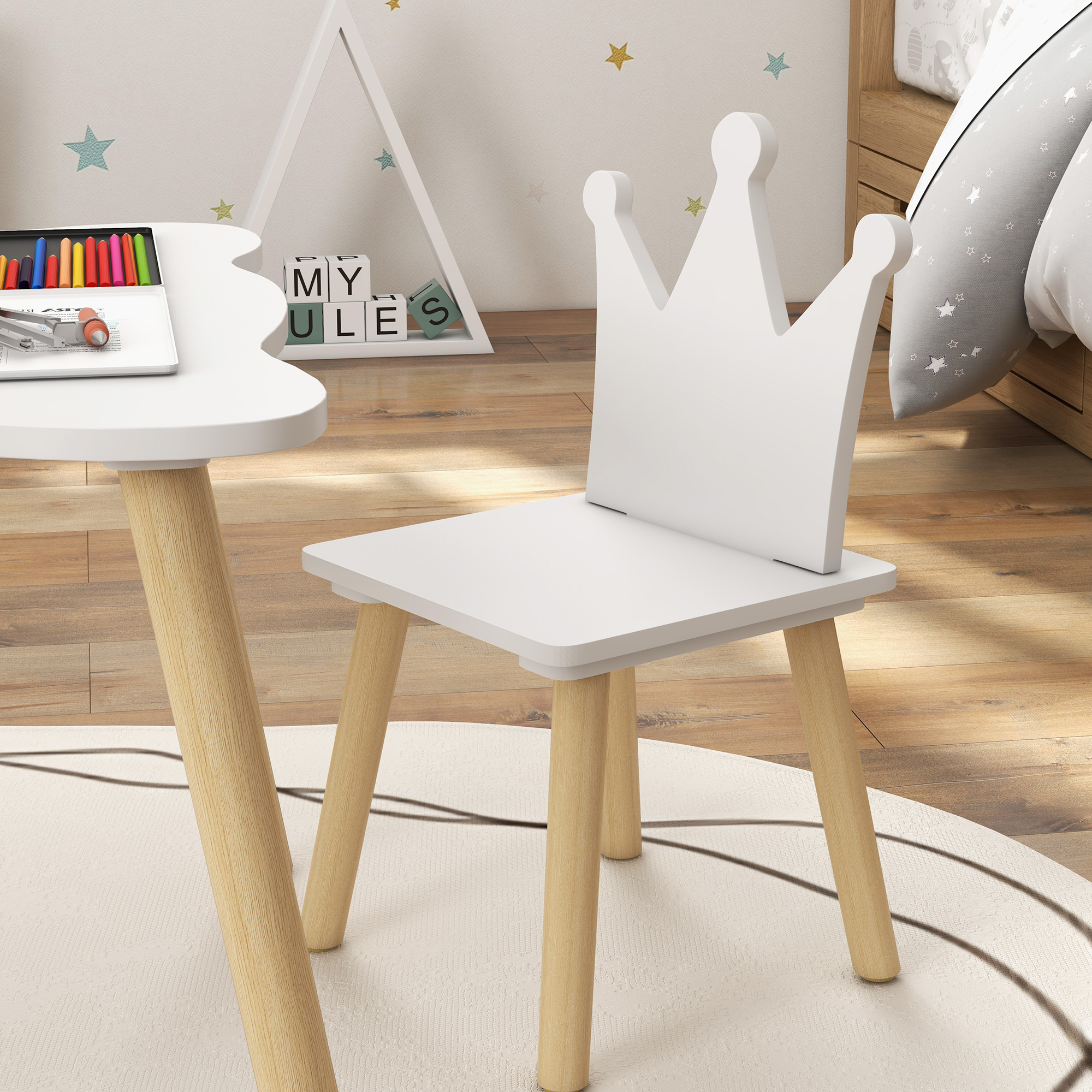 Una silla y mesa con corona blanca, crayones y bloques están en una habitación infantil. El fondo tiene calcomanías de estrellas.