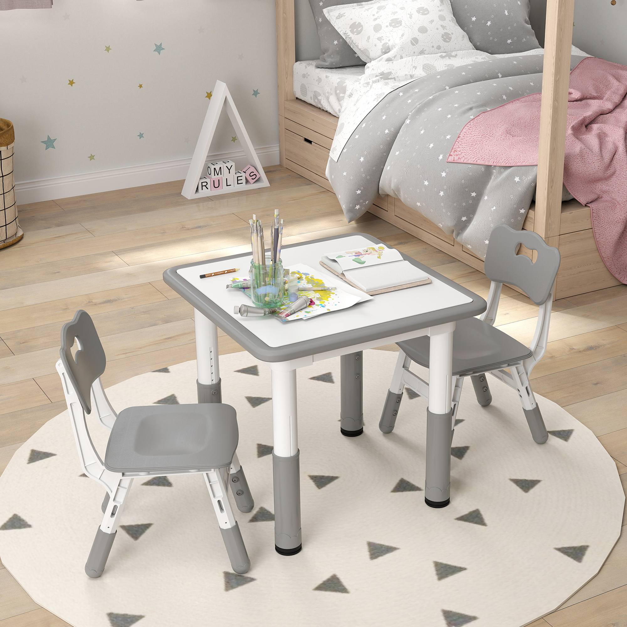 Una habitación infantil con una mesa, dos sillas y una cama. La mesa tiene útiles de arte. Una alfombra con triángulos está en el suelo.