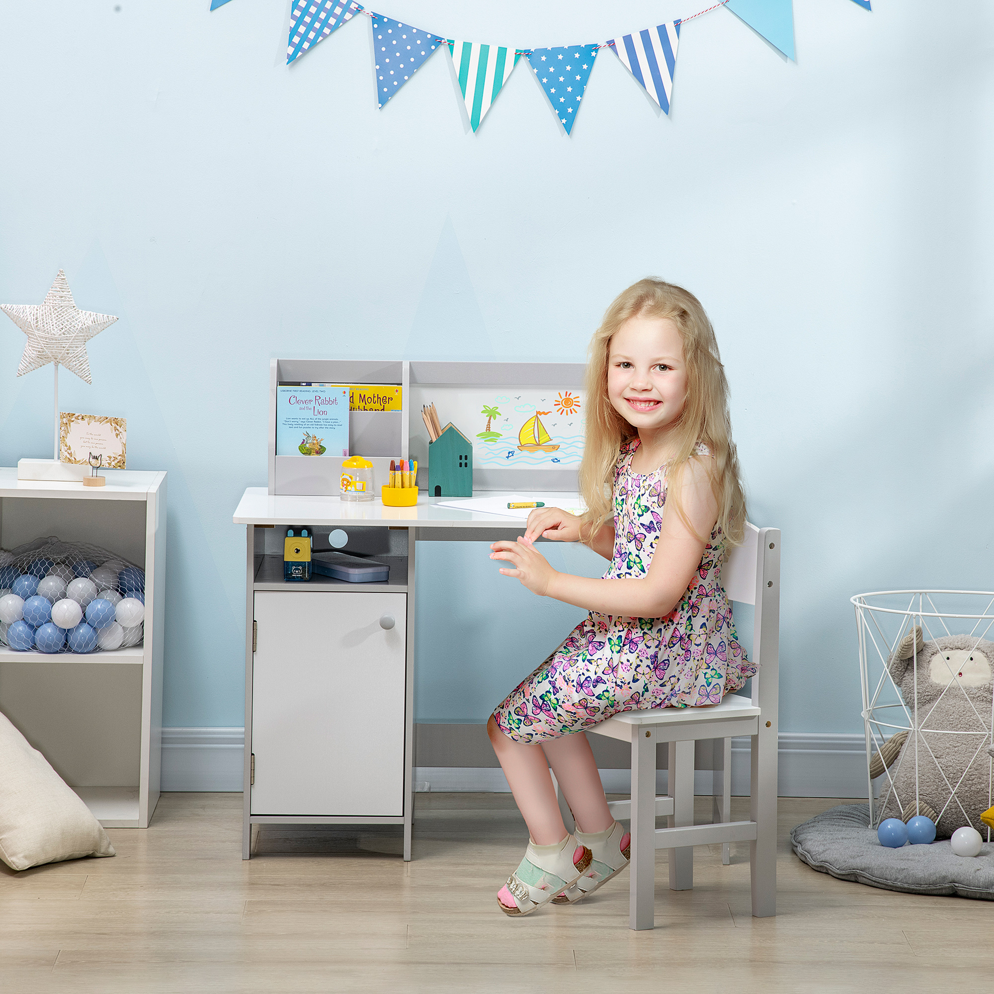 Una bambina seduta a una scrivania in una stanza con pareti blu, decorazioni a stella e gagliardetti colorati.