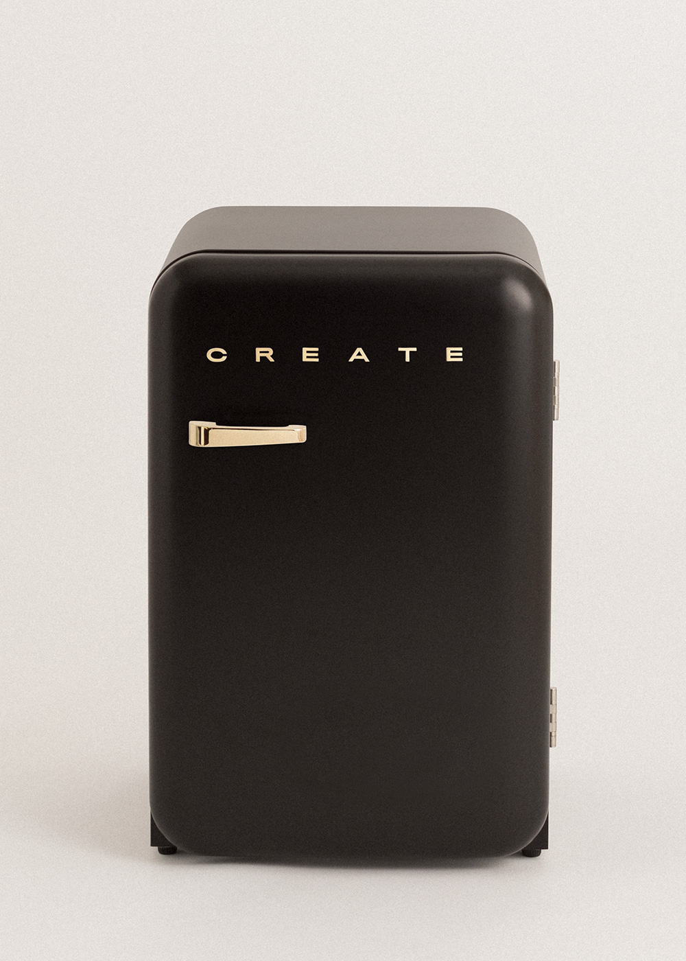 Un mini-refrigerador negro con asa dorada y letras 'CREATE'. Sobre fondo blanco.