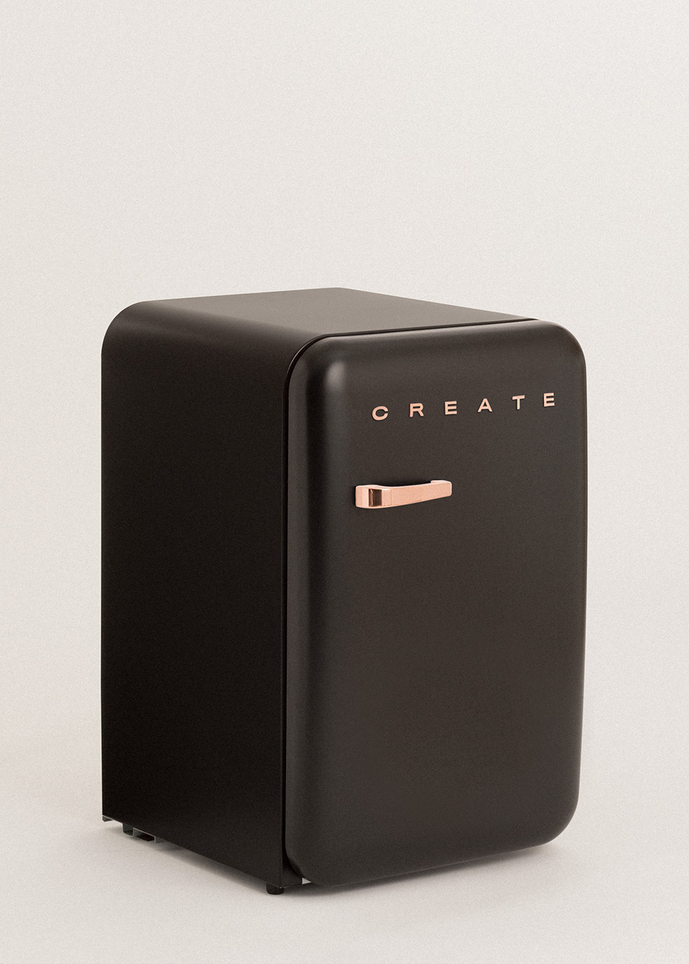 Un pequeño refrigerador negro con manija dorada y letras 'CREATE'. Está sobre una superficie blanca.