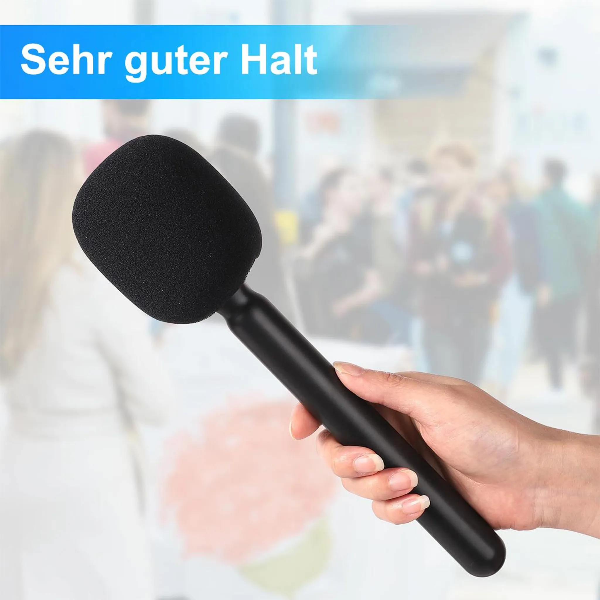 Eine Hand hält ein schwarzes Mikrofon mit Schaumstoffkopf. Der Hintergrund ist eine verschwommene Menschenmenge.