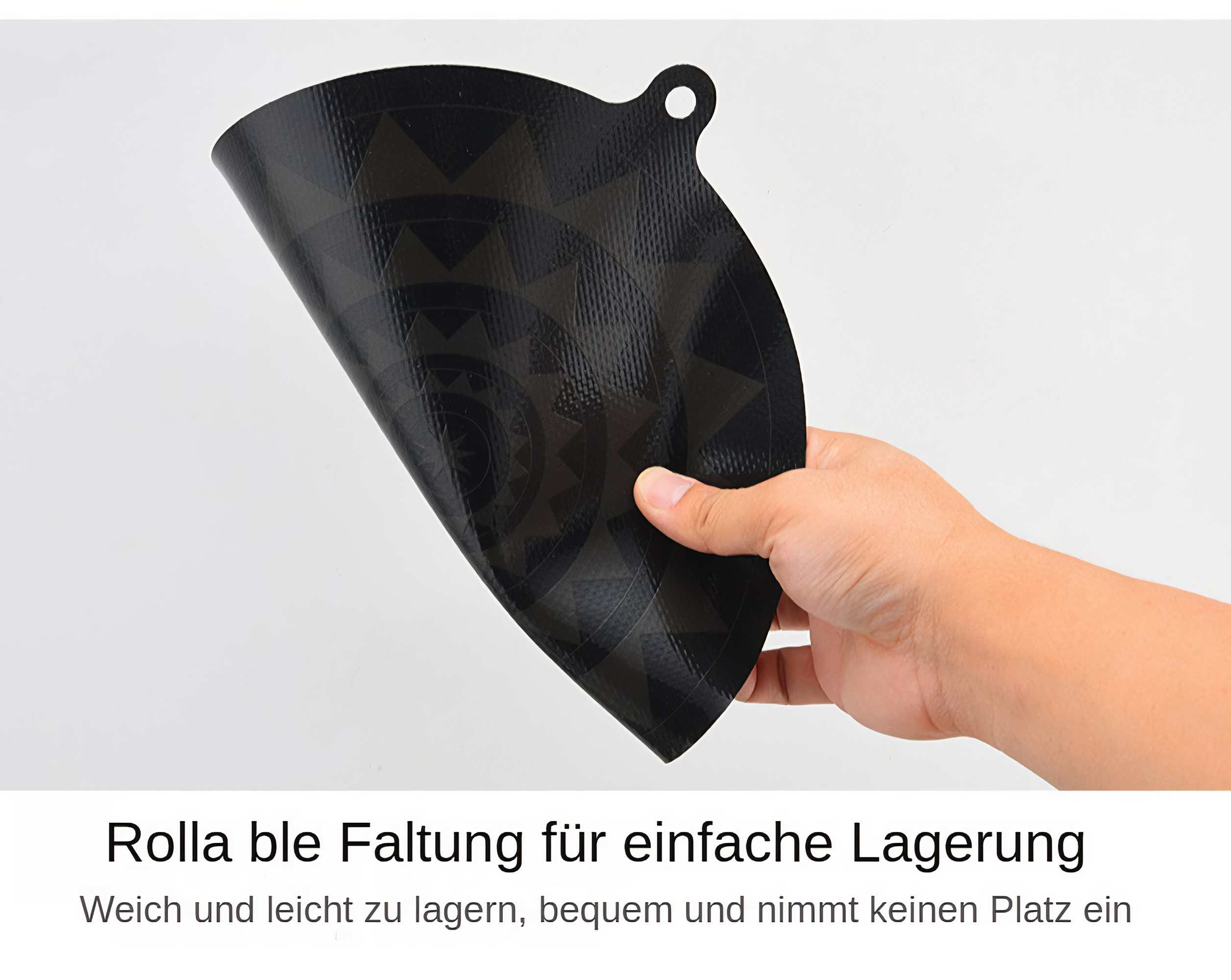 Eine Hand hält eine schwarze, gemusterte, flexible Matte. Sie hat oben ein Loch. Der Hintergrund ist weiß.