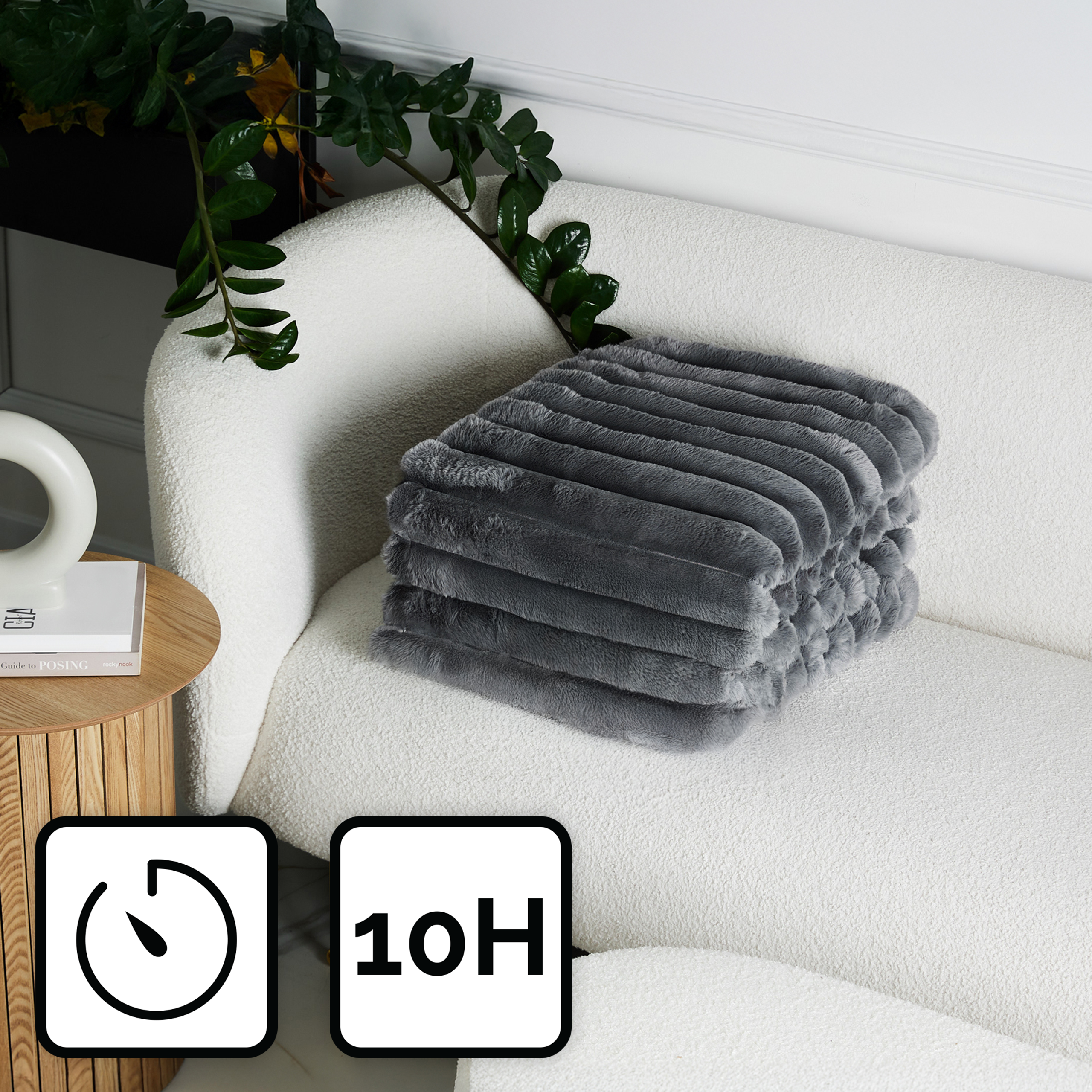 Szara narzuta z imitacji futra jest starannie złożona na białej kanapie. Na dole zegar i tekst '10H'.