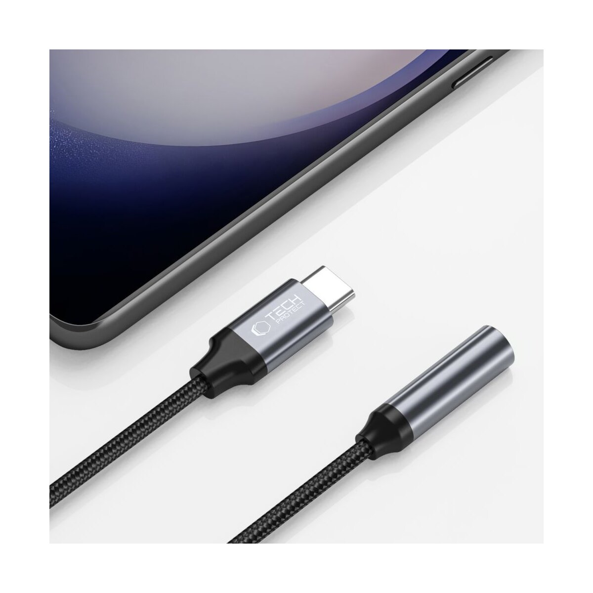 A phone and two adapters. One is a USB-C and the other is a 3.5mm audio jack, connected by a black braided cable.