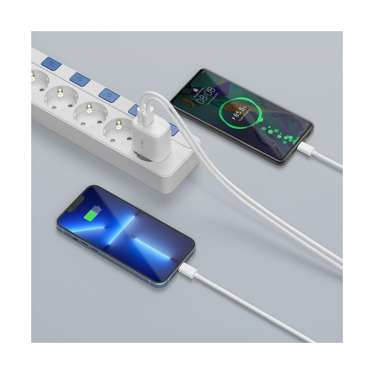 Deux smartphones en charge, connectés à une multiprise via des câbles blancs et un chargeur blanc.