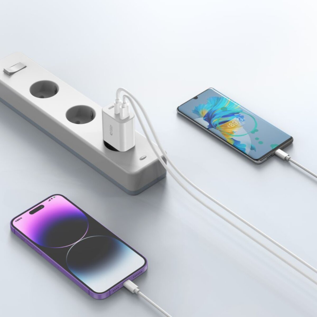 Een stekkerdoos met aangesloten oplader, twee telefoons die opladen. Eén telefoon toont een kleurrijke afbeelding, een ander een paarse gradiënt.